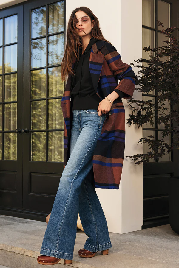 Stylish plaid outfits for women featuring a long brown and navy striped plaid coat layered over a black hoodie and wide-leg jeans, accessorized with sunglasses and brown Stiletto