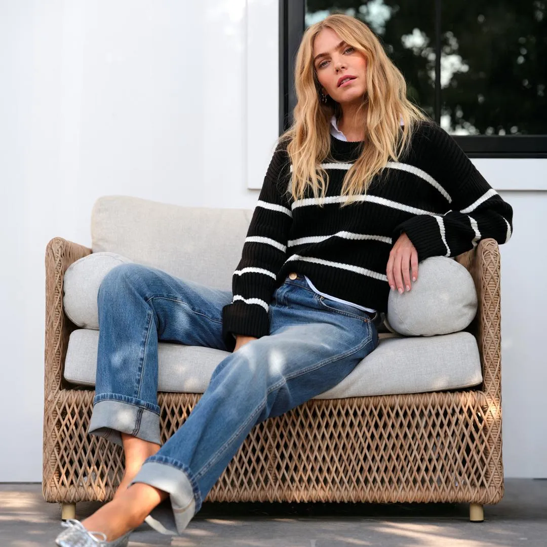 A capsule wardrobe essential featuring a black and white striped sweater paired with cuffed denim jeans, showing how to build a versatile capsule wardrobe with classic pieces