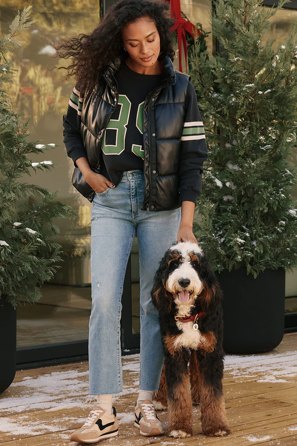 How to wear a graphic tee demonstrated with a sporty varsity-style graphic tee paired with light wash jeans and a puffer jacket, showing a casual weekend style